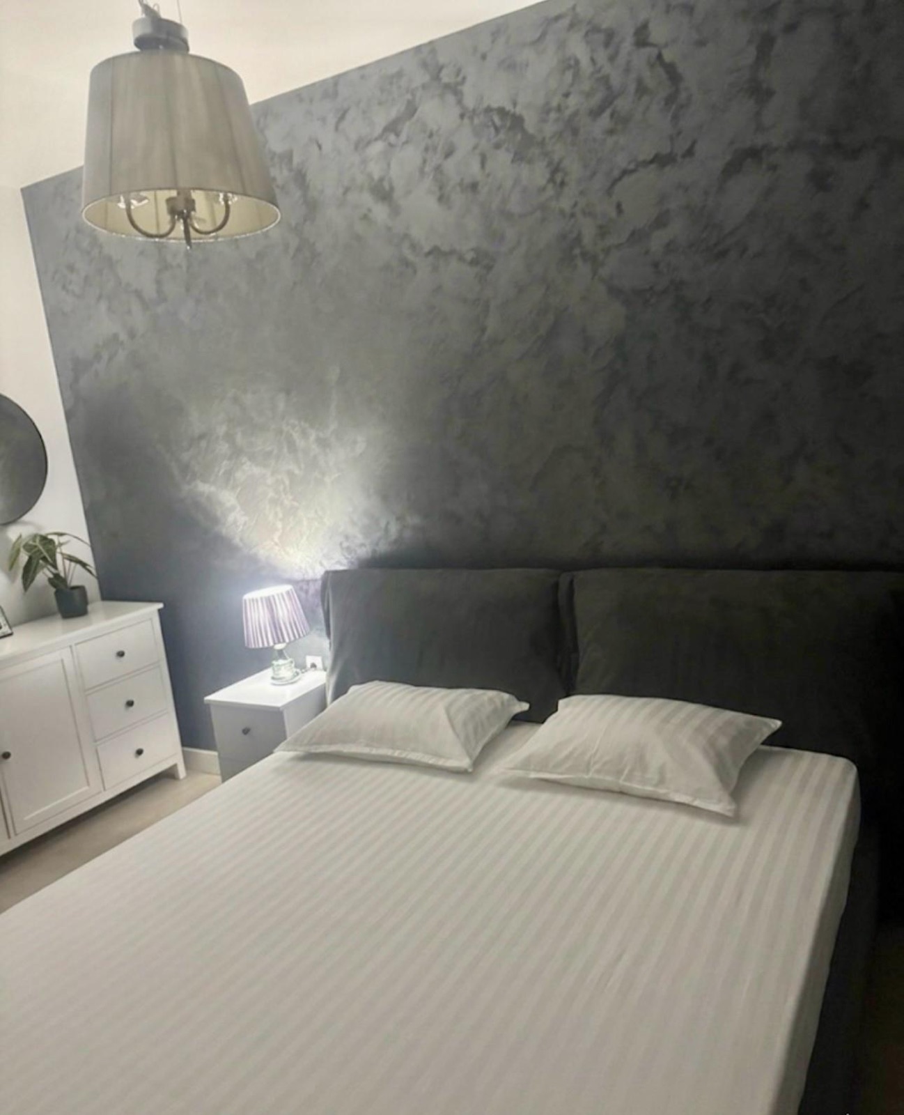 Dormitor cu perete din tencuială decorativă și comodă